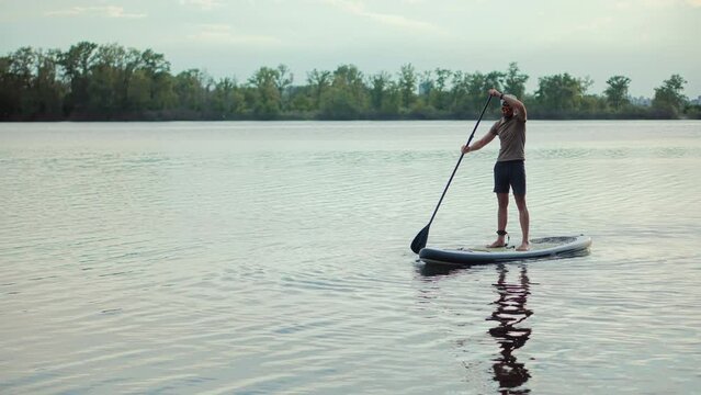 Strong man swims while surfing beside boat	