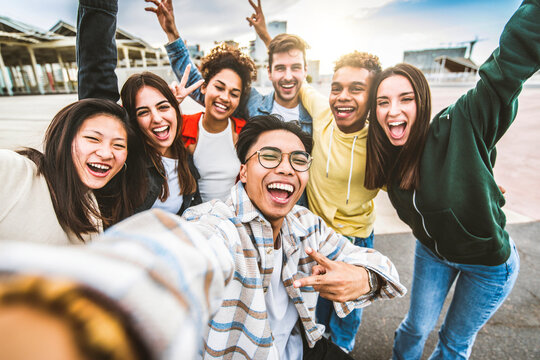 Multicultural happy friends having fun taking selfie group photo portrait outside - University students smiling together at camera in college campus - Teenagers hanging out on city street