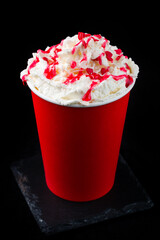 Hot chocolate or cocoa with whipped cream and cherry topping in red paper cup