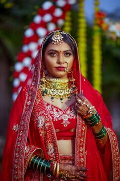 Magnificent young Indian bride in luxurious bridal costume with makeup and heavy jewelry, outdoor Photoshoot. Wedding fashion.