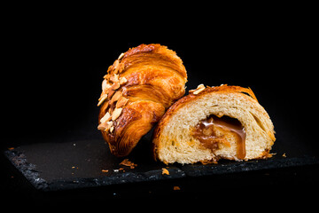 French breakfast cut fresh croissant with caramel and almond petals.