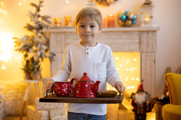 Cute preschool child, blond boy with pet dog, playing in decorated Christmas room
