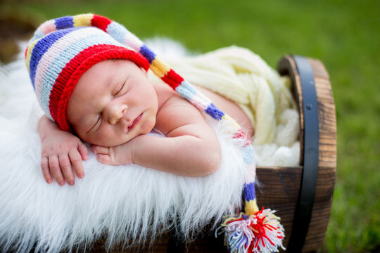 Little sweet newborn baby boy, sleeping in crate with knitted pants and hat in garden