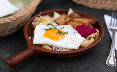 Scrambled eggs with fried bacon and potatoes served on plate