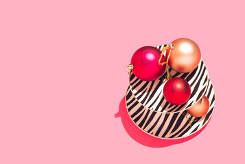Christmas balls in red and gold colors on cake stand. Minimal New Year's concept on pink background. Flat lay.