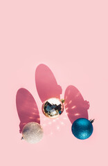 Christmas balls in blue and silver colors on pastel pink background. Minimal New Year's concept. Flat lay.