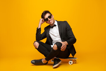 Stylish man sitting on skateboard