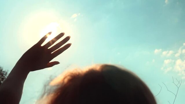 woman soak up sunshine . hand playing with sun rays .