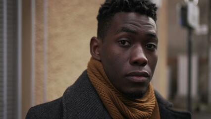 Portrait young black man staring at camera outside in urban european city town