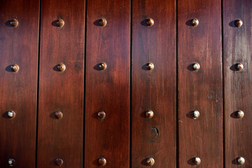 A solid wooden door close-up with rows of metal studs
