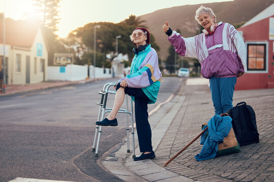 Hitchhiking, Disability And Travel With Senior Friends Standing On A Corner Looking For A Trip With A Hand Sign Or Gesture. Transport, Road And Handicap With A Mature Woman And Friend Hitching A Ride