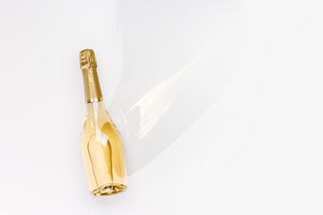 Top view white sparkling wine bottle with sunshine long shadow and flare on light white background....