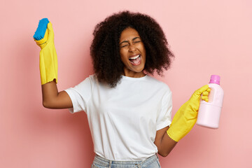 Woman celebrates the end of cleaning, she wears yellow cleaning gloves and holds blue brush