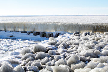 Ice sculptures and frozen water on the pier and dam of the Afsluitdijk, the giant dike of The Netherlands. A blue sky and white rime ice make a beautiful composition in this winter cold scene