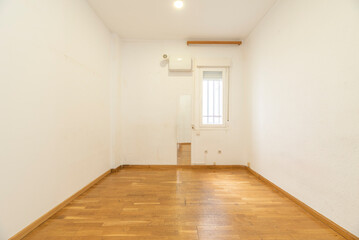 Empty living room with an oak parquet floor and a window and a mirror on the wall