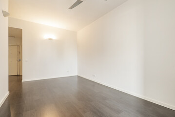 Empty living room with dark laminate flooring and unadorned plain white walls