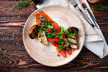 Italian cuisine salmon carpaccio with olive tapenade, hot peppers, herbs and croutons.