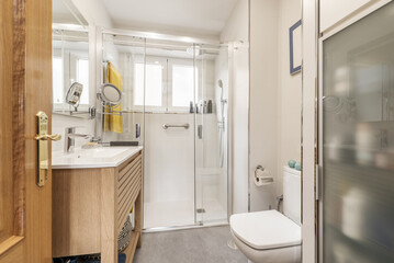 Bathroom with oak furniture, shower cabin and circular beauty mirror with light