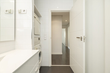 Fototapeta na wymiar Bathroom with plain white cabinets with frameless mirrors and a washer and dryer column