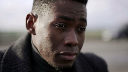 Pensive worried black African man feeling anxious and concerned sitting outside in sidewalk curb2