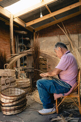 South American craftsman sitting on his chair while weaving wicker basket