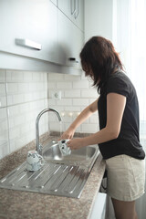 Young girl is washing dishes. The teenager helps with home routine