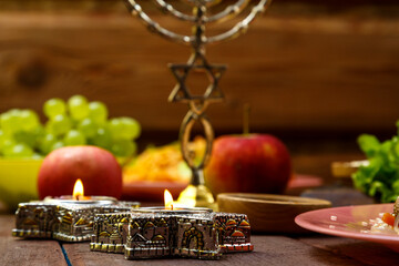 Shabbat burning candles. Traditional Jewish dishes on the set table, fruits, menorah.