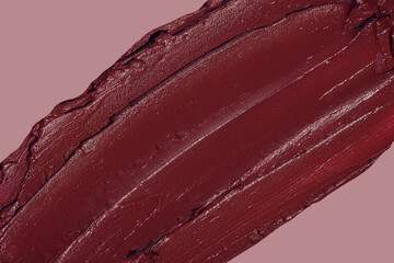 Smashed red lipstick texture smear close up macro flat lay on pink background with copy space. Cosmetic beauty product sample smudge demonstration. Creative make up shot.