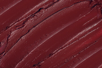 Smashed red lipstick texture smear close up macro flat lay background with copy space. Cosmetic beauty product sample smudge demonstration. Creative make up shot.