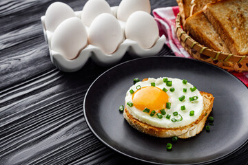 delicious fried egg sandwich on black rustic wooden background