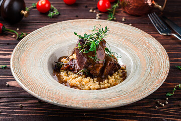 Restaurant lunch stewed beef cheeks with ptitim risotto with demiglace sauce.