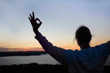 Fototapeta na wymiar closeup of the silhouette of a woman performing a yoga asana at sunrise looking at the sea