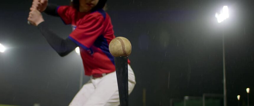 Portrait of Caucasian kid boy baseball player practicing hits alone on a rainy evening. Shot with anamorphic lens