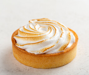 Small lemon curd tart covered with meringue, light background