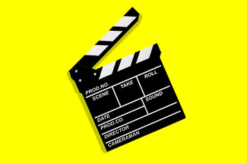 Fototapeta na wymiar Clapperboard for shooting video footage takes on a yellow background