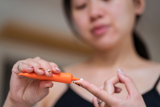 Asian woman applying cream on finger