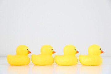 A row of four yellow rubber ducks lined up in single file facing rightward direction, idiomatic and phrase concept for organisation, to get one’s ducks in a row, business and work speak