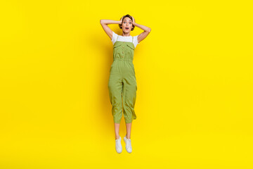 Fototapeta na wymiar Full body photo of attractive funky jumping trampoline girl touch head forgot turn off her iron home unexpected isolated on yellow color background