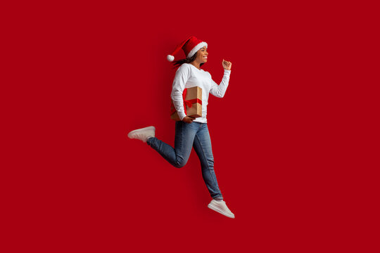 Emotional young black woman jumping with xmas gift