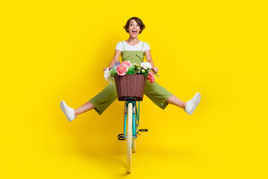 Full size photo of nice young girl driving cycle fast hurry scream energetic wear trendy khaki clothes isolated on yellow color background