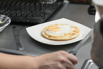 typical colombian breakfast served on a white plate on top of a metal plate. arepa with eggs and small eggs to be eaten.