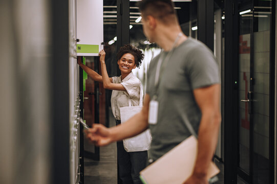 Joyful office worker and her coworker opening section lockers