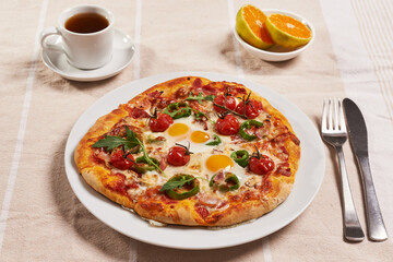 breakfast pizza with eggs, cup of coffee and oranges