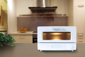 white modern design toaster oven is on the brown wooden table with background of nice dinner kitchen room during breakfast