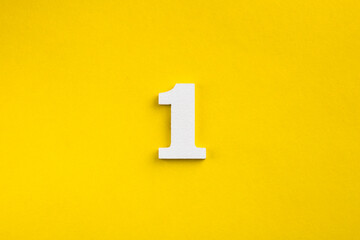 Number one - white number in wood on yellow background - obrazy, fototapety, plakaty