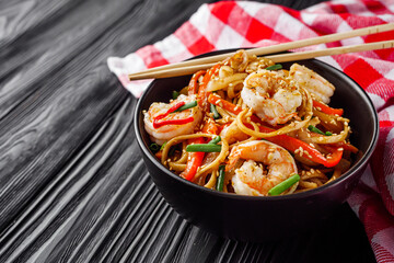 fried wok shrimp noodles on a black wooden rustic background