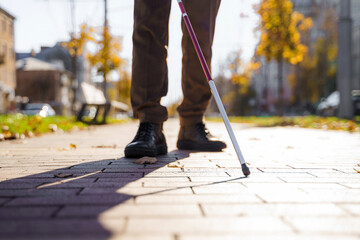 Close-up of a blind man with a walking stick on the alley of the city