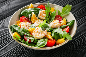 delicious fresh shrimp salad with orange and cherry tomatoes on a black wooden rustic background