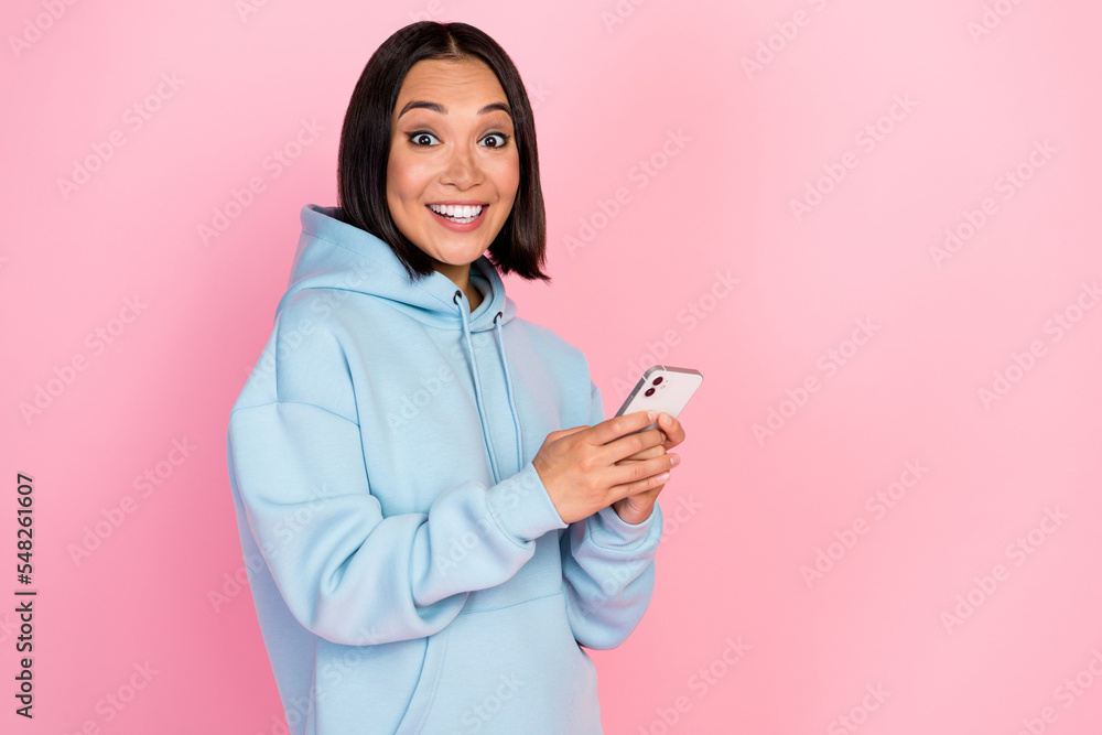 Sticker Photo of excited funny girl dressed blue sweatshirt writing message modern gadget empty space isolated pink color background