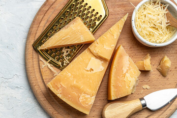 Parmesan cheese on a wooden board, Hard cheese, olives, rosemary and metal grater on a light...
